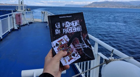 Il libro Il fante di picche tenuto in mano a bordo di una nave